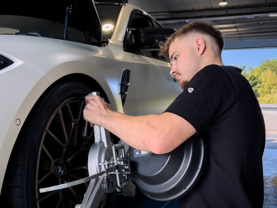 Mechaniker setzt den Messkopf für die Achsvermessung am Vorderrad an