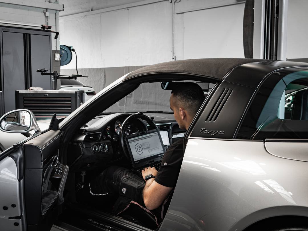 Computerdiagnose im Fahrzeuginnenraum mit Laptop auf dem Fahrersitz