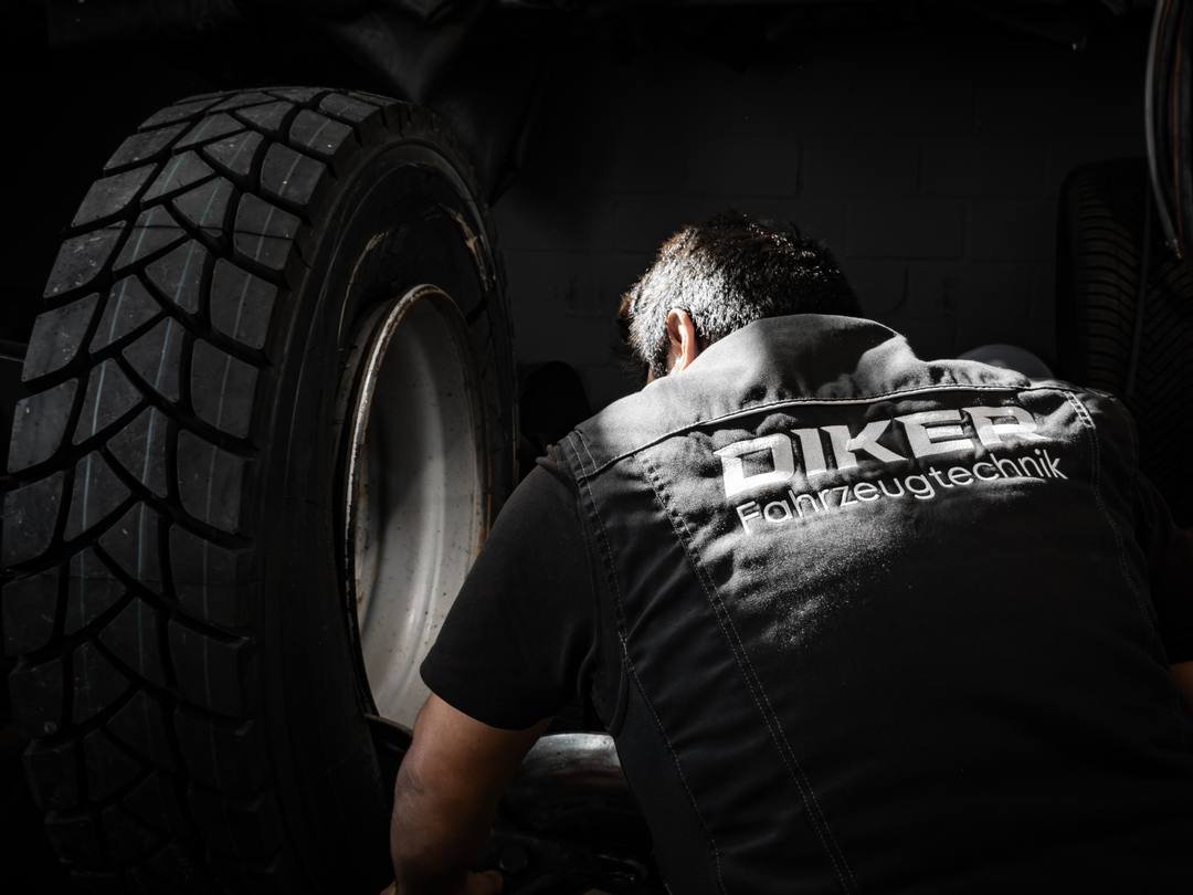 Mechaniker in Diker-Arbeitsweste bei der Montage eines LKW-Reifens