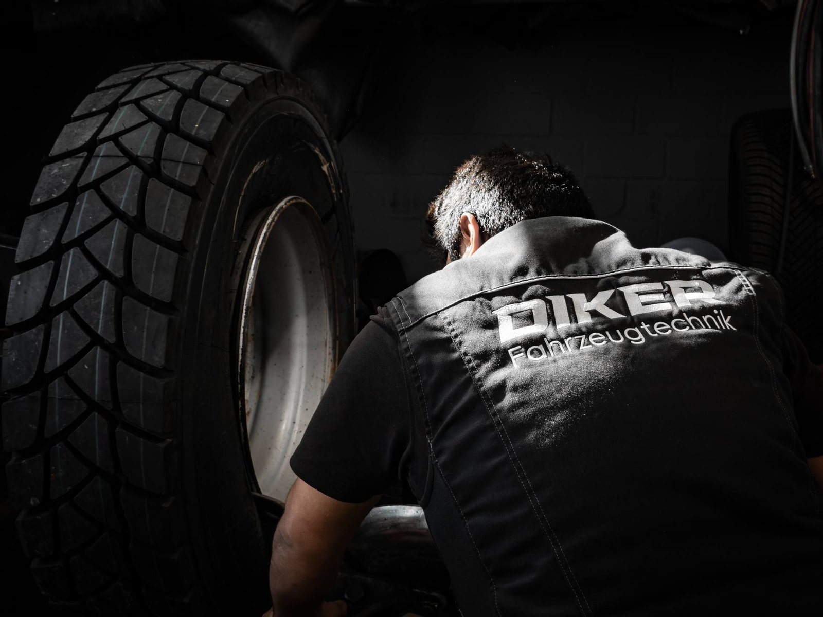 Mechaniker in Diker-Arbeitsweste bei der Montage eines LKW-Reifens