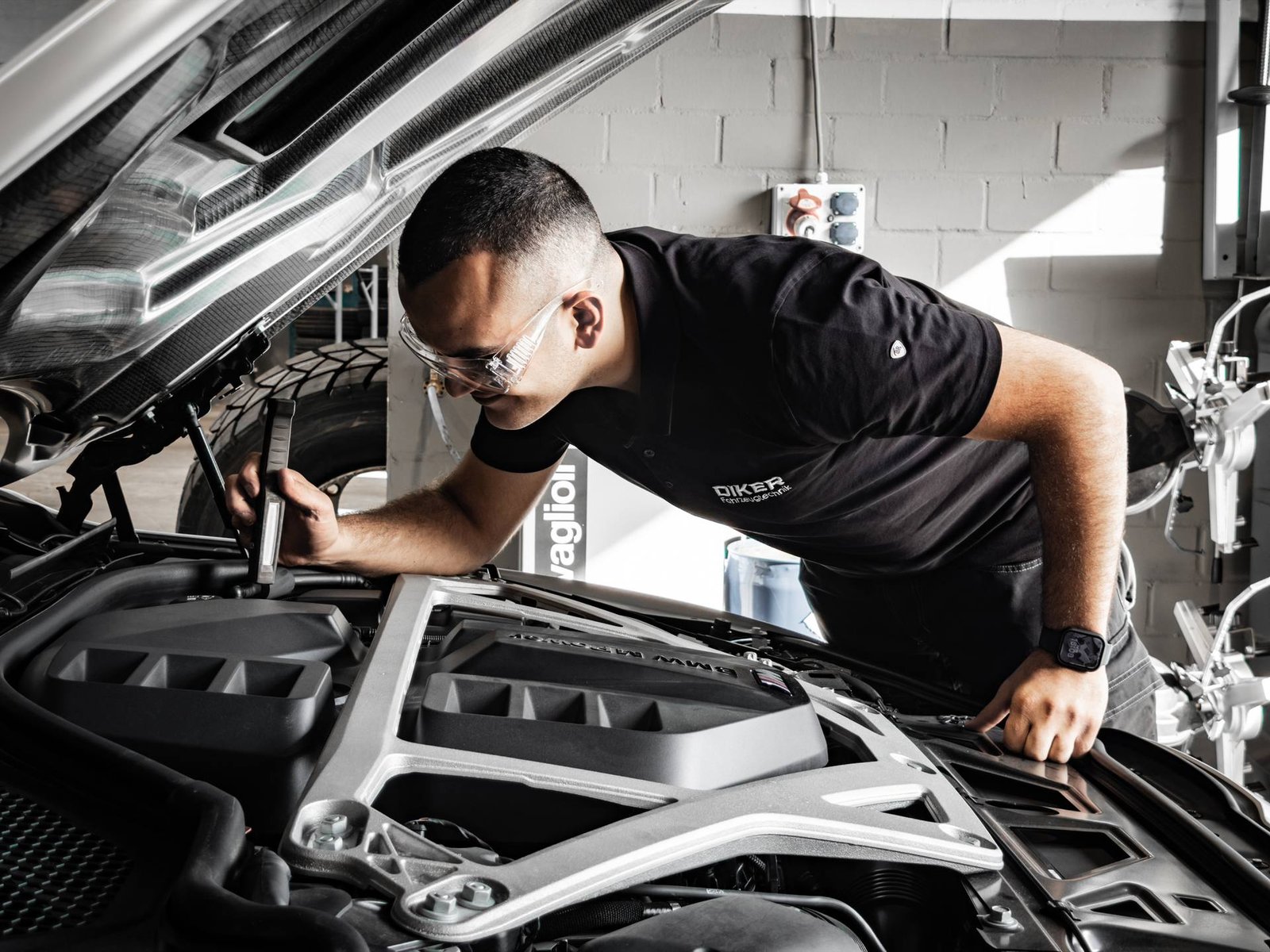 Mechaniker mit Schutzbrille bei der Inspektion im Motorraum