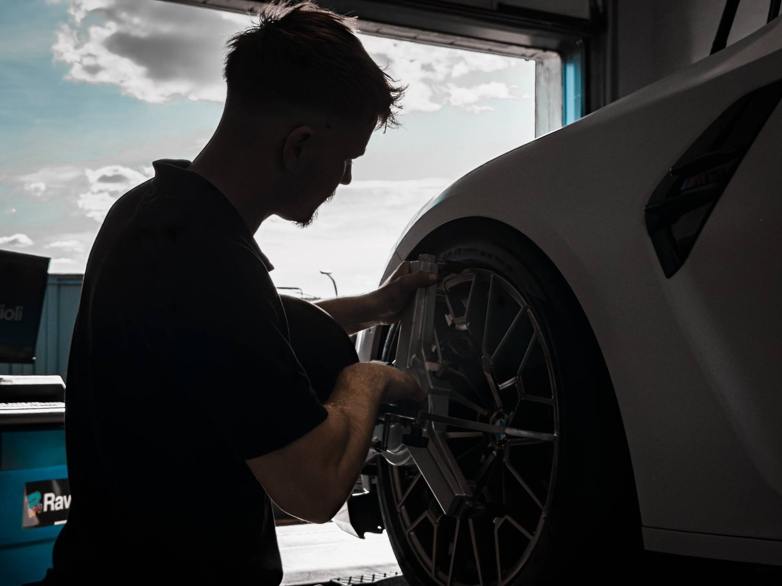 Radmontage an einem Sportwagen im Gegenlicht des Werkstatttors